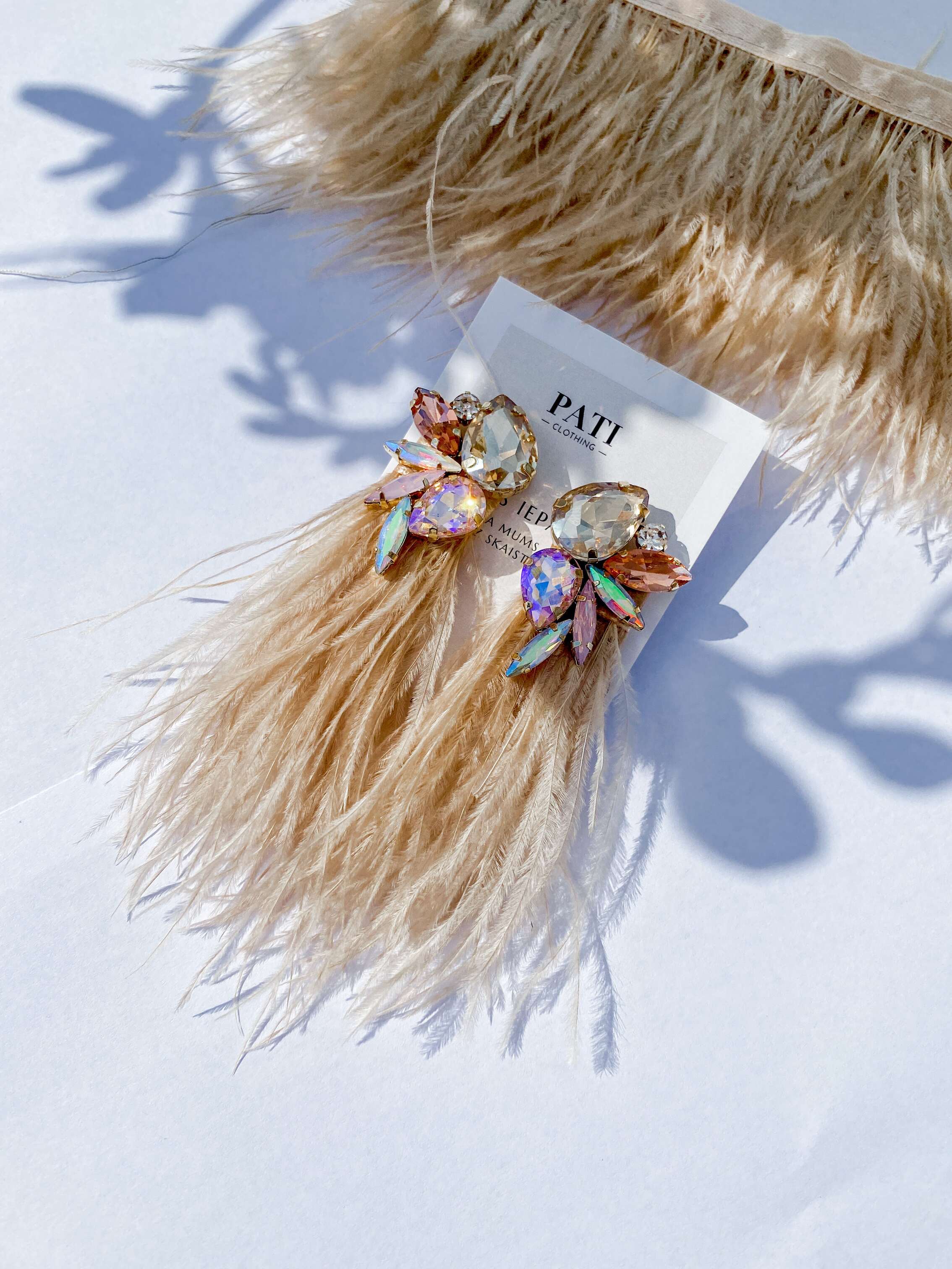 hand-made feather earrings with crystals on white background editorial photo